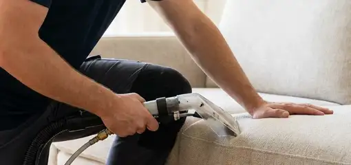 Professional upholstery cleaner deep-cleaning a fabric sofa with a handheld extraction tool, Baton Rouge, LA.